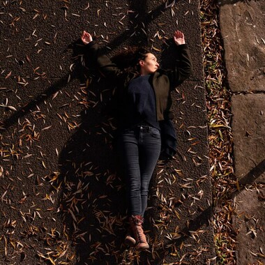 Raquel Meseguer lies on the street. There are leaves all around her.
