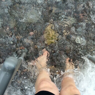 Nackte Füße, die in einem fließenden Gewässer stehen.