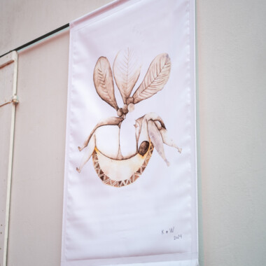Ein Banner mit Zeichnungen, das an der weißen Hauswand des Gartenhaus Haeckel hängt.