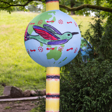 Air-filled itaaká hanging in a tree, colourfully painted with animals and landscapes.