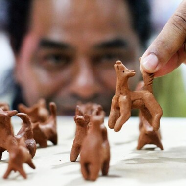 Irineu Nje'a Terena mit mehreren kleinen Figuren aus Keramik.