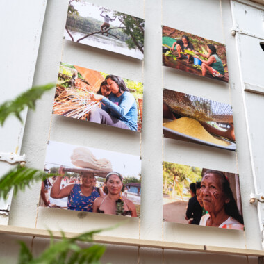 Sechs große Fotos von Menschen, die an der weißen Hauswand des Gartenhaus Haeckel hängen.