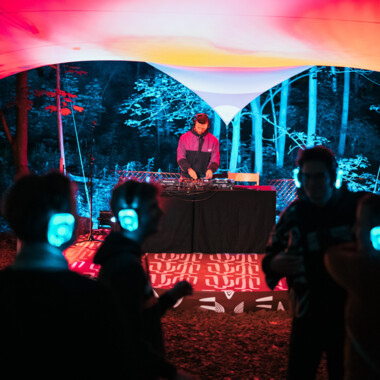 Personen mit blau leuchtenden Kopfhörern tanzend im Festivalzentrum.